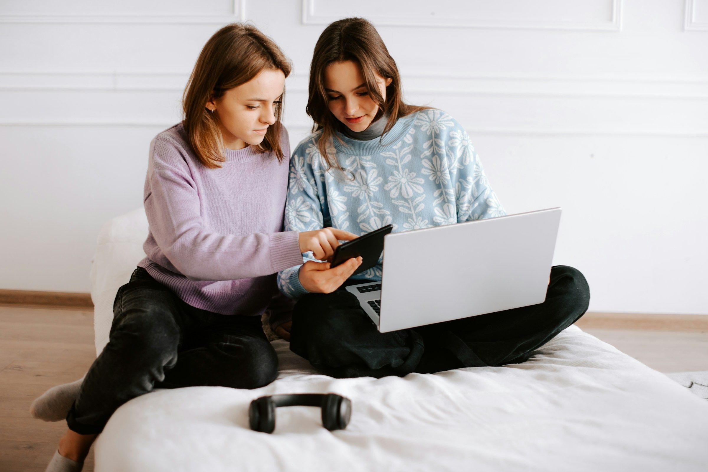 girls using a laptop on a bed - Opus Clip