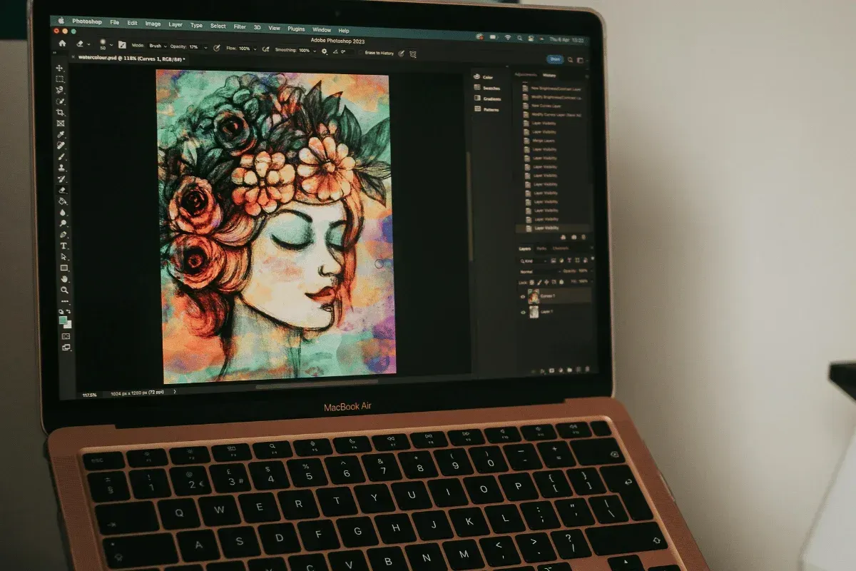 Ein Laptop zeigt digitale Kunst in Adobe Photoshop: ein ruhiges Frauenporträt mit Blumen im Haar. Das Bild ist lebendig und farbenfroh.