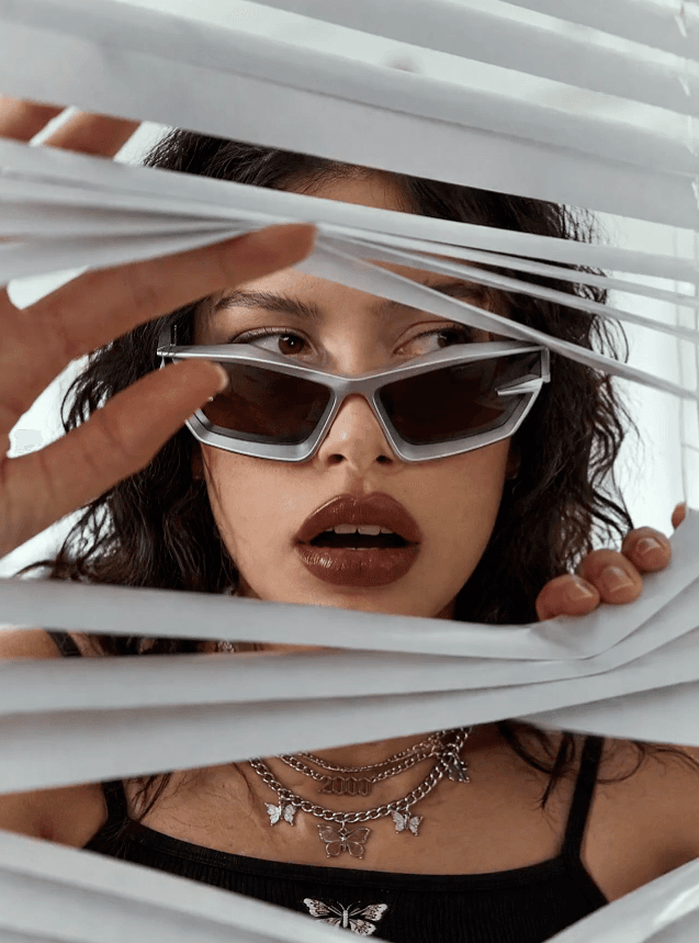 GPT Image 2.5 portrait of a woman wearing sunglasses and looking through white blinds.